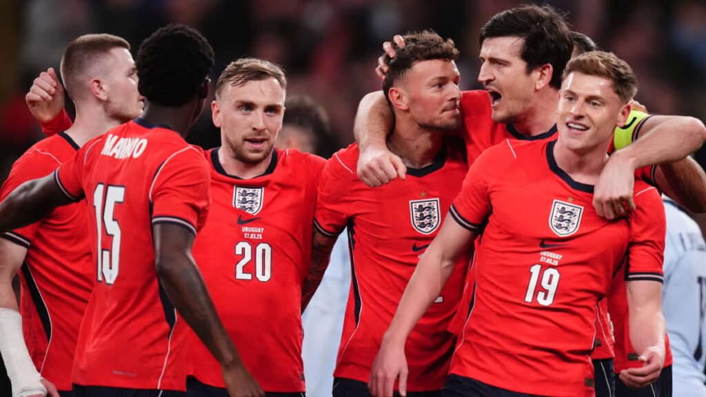 Ben White celebrates a goal for the England national team while being embraced by his teammates in red shirts