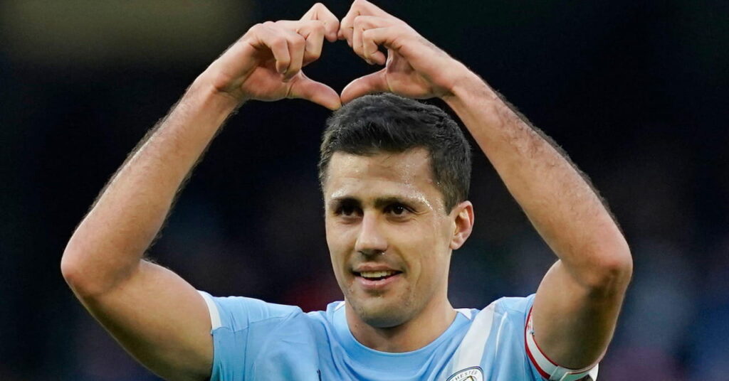 Spain and Manchester City footballer Rodri making a heart sign by lifting his hands and smiling while playing in the primary colours of light blue with white trim of Premier League team Man City