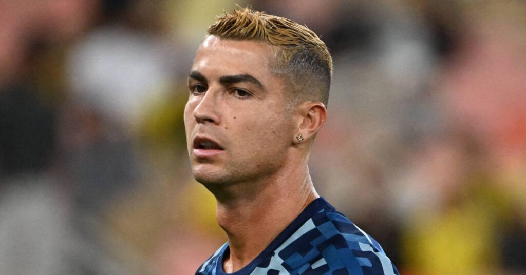 Portugal footballer Cristiano Ronaldo looking to his right on a pitch while playing for Saudi Pro League team Al Nassr Football Club in a dark and light blue shirt