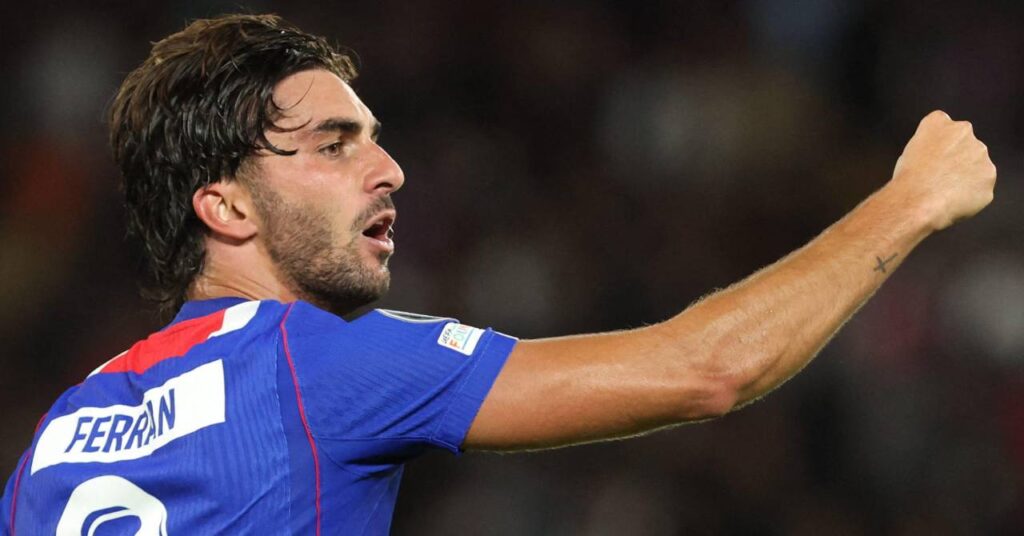 Spain footballer Ferran Torres raising his right fist to celebrate a goal while playing for French Ligue One club Paris Saint Germain in a blue PSG shirt with his name and number in white on the back and red trim
